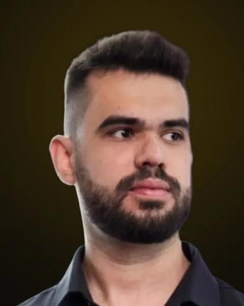 Alex Gurrão de camisa preta, olhando para o lado, sobre fundo escuro